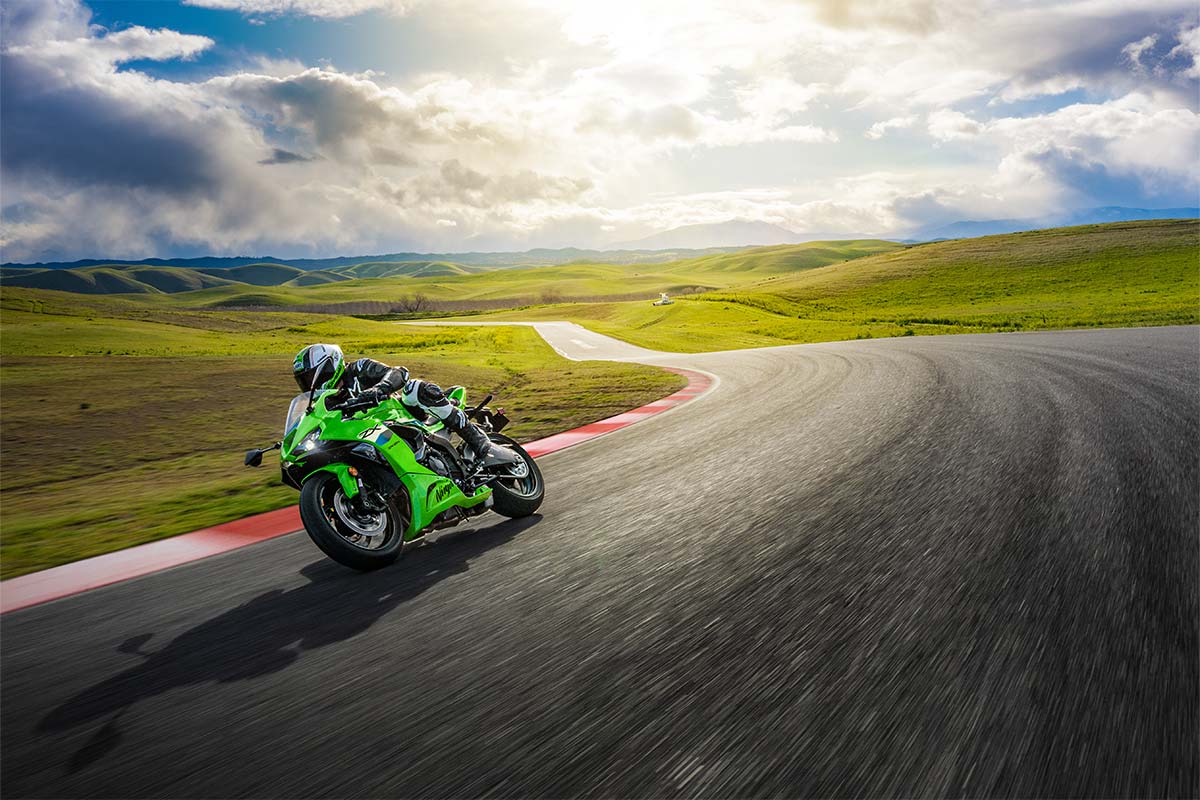 kawasaki-ninja-zx-6R-2026-chinh-hang-MAXMOTO-1 Người lái xe Kawasaki Ninja xanh lá cây ôm cua trên đường đua giữa khung cảnh đồi núi